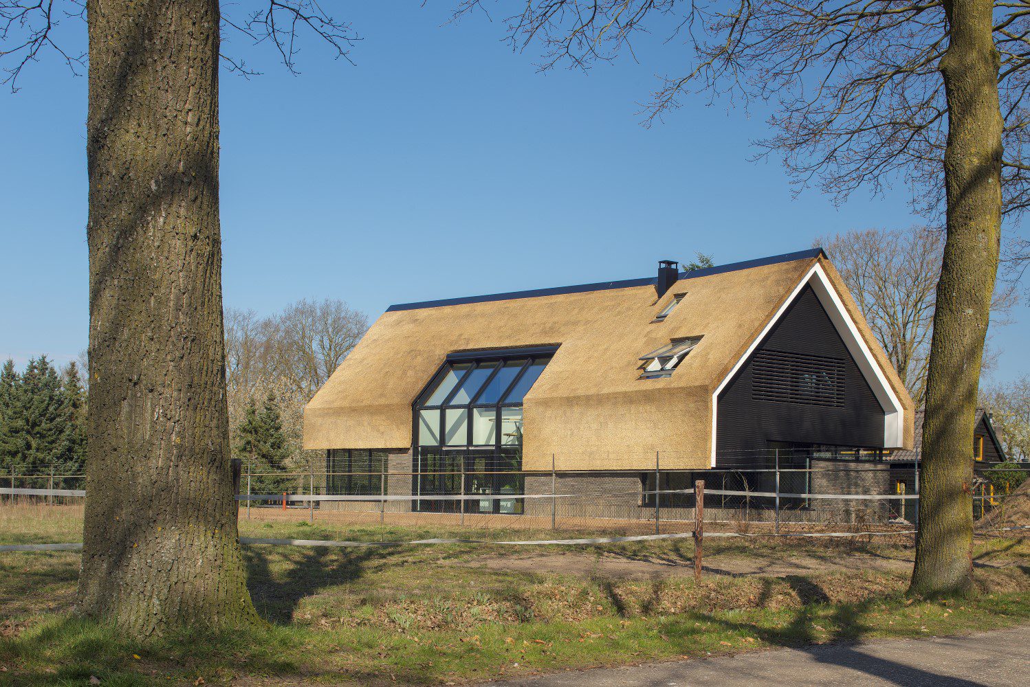 Rietgedekte villa met zwarte kozijnen en uitkijk op vide